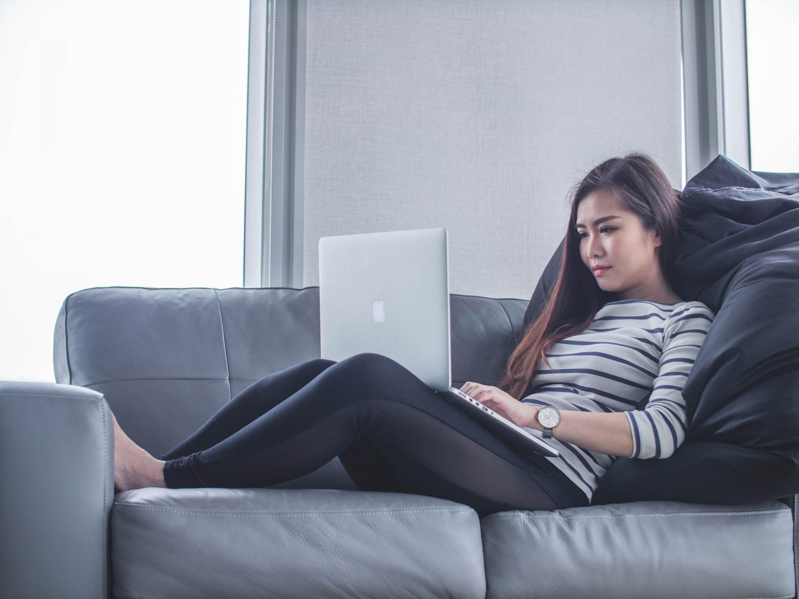 women sitting on couch with laptop