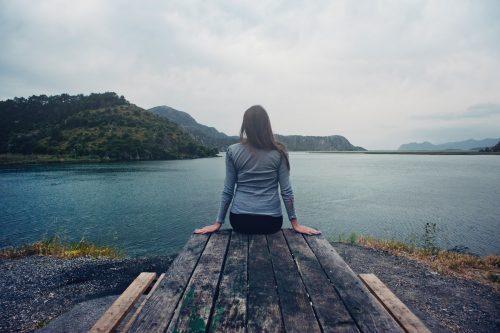 Woman sitting on dock next to a lake