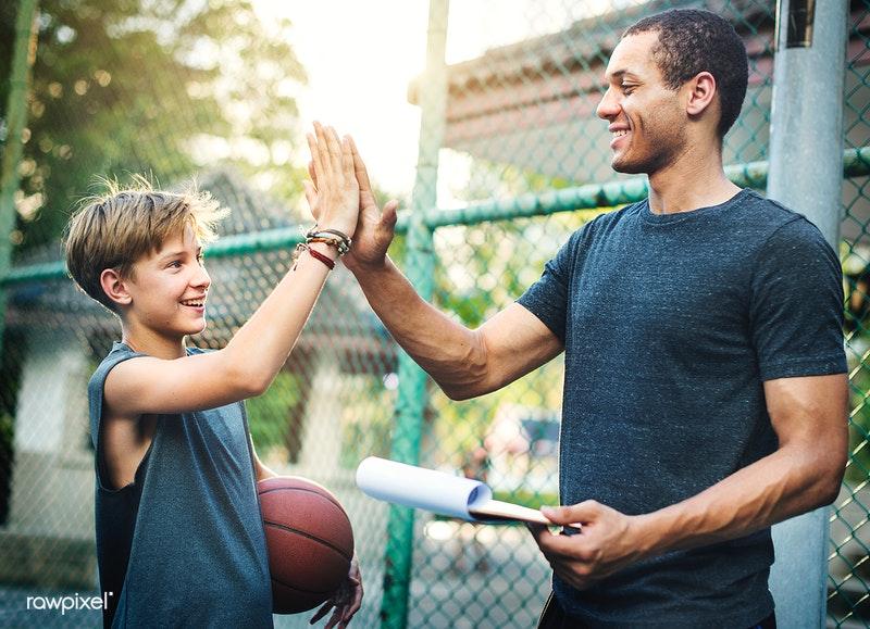 Coach giving a high five to child with a basketball