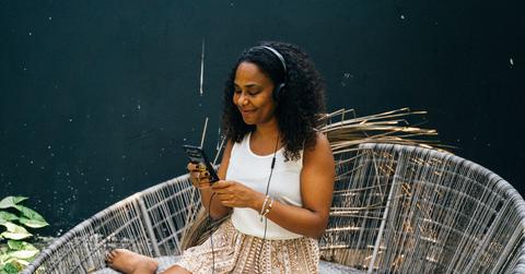 Woman sitting in chair outside listening to podcast