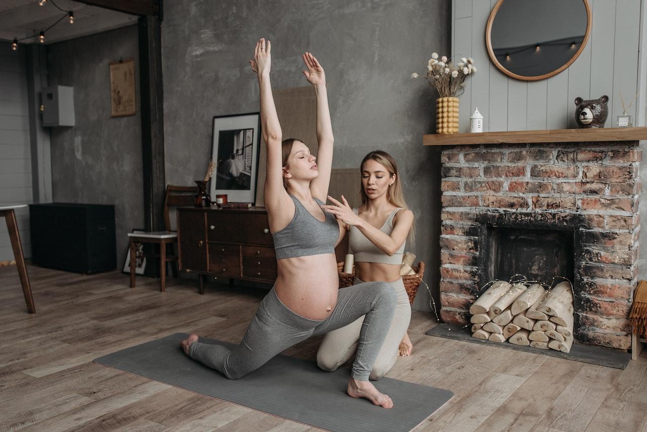 trainer helping pregnant woman exercise