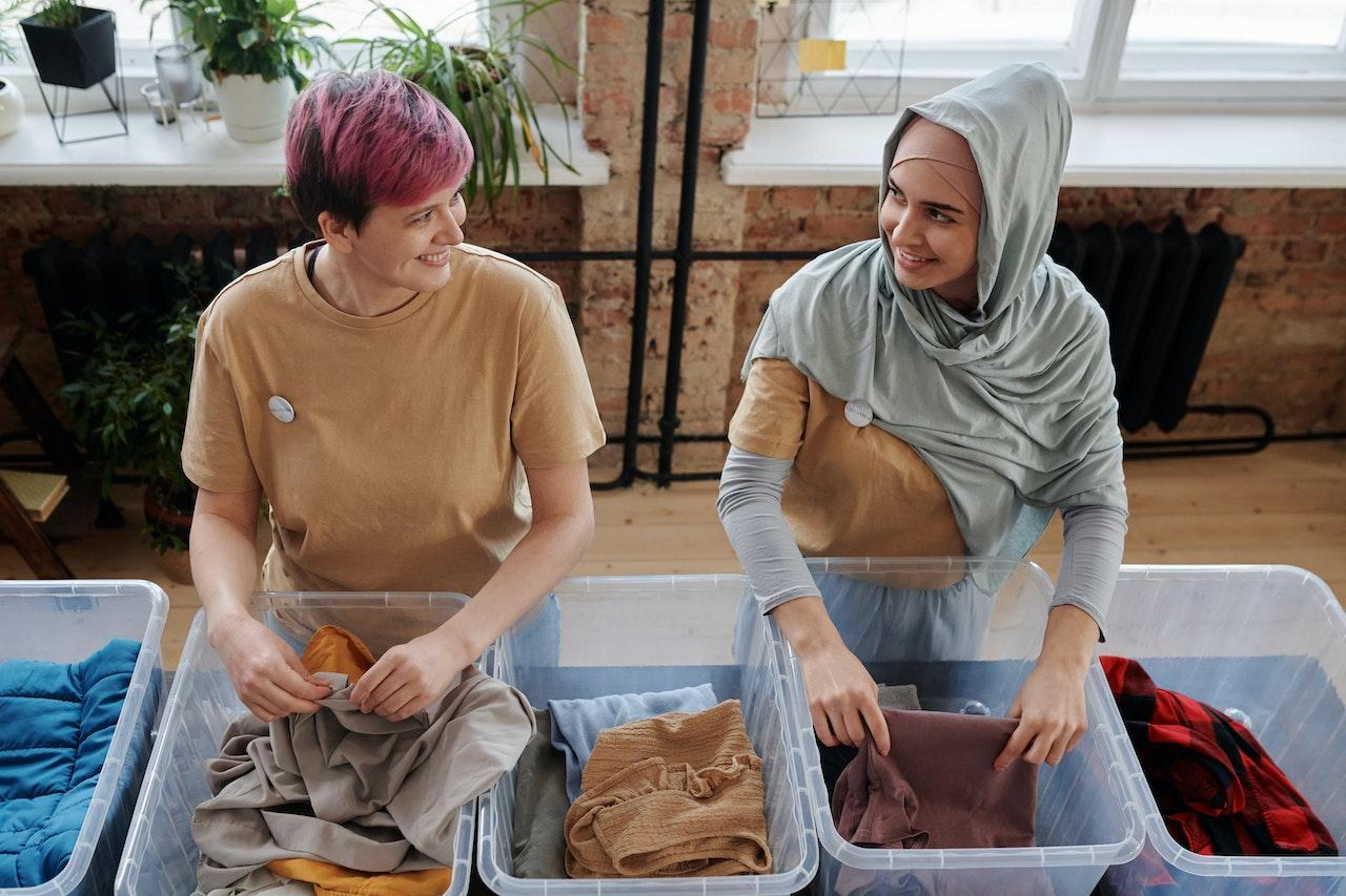 Women sorting bins of clothes. 