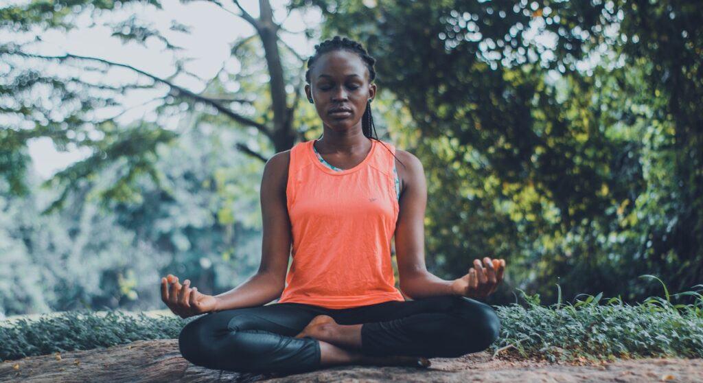 Black woman in an orange shirt meditating