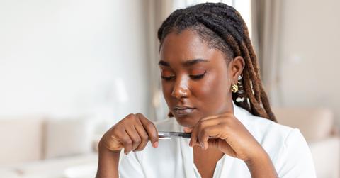 Serious frowning African American ethnicity woman sit at workplace desk looks at laptop screen read e-mail feels concerned. Bored unmotivated tired employee, problems difficulties with app