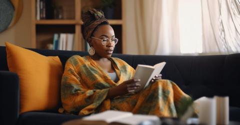 African american woman reading on couch at home, relaxing in her apartment on the weekend quiet childfree lifestyle independent woman Ai generated