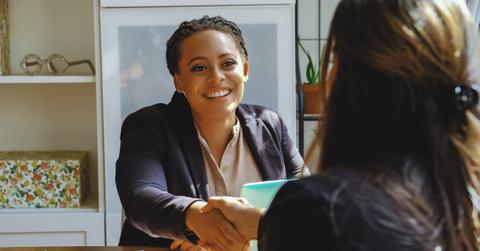 smiling Young adult black executive businesswoman handshake with client in office