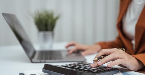 Close up hands of woman in brown formal suit checking bills, taxes, bank account balance, using calculator, Personal Checking, Empower Checking, Personal Savings, Certificates, IRAs, Money Market
