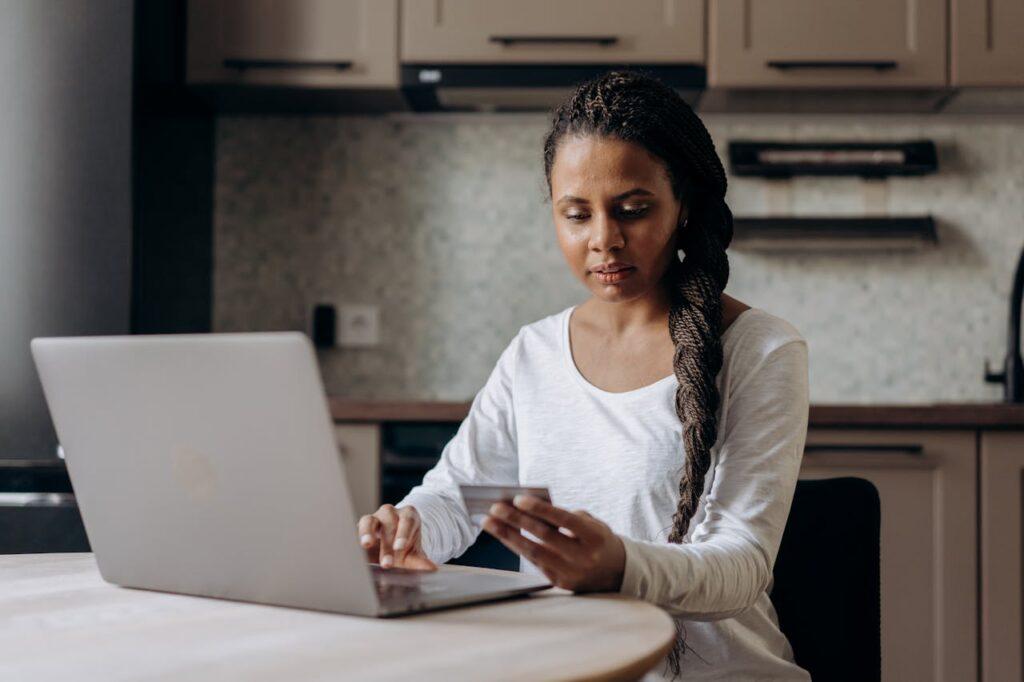 Woman sitting at her desk with her laptop and credit card in hand.