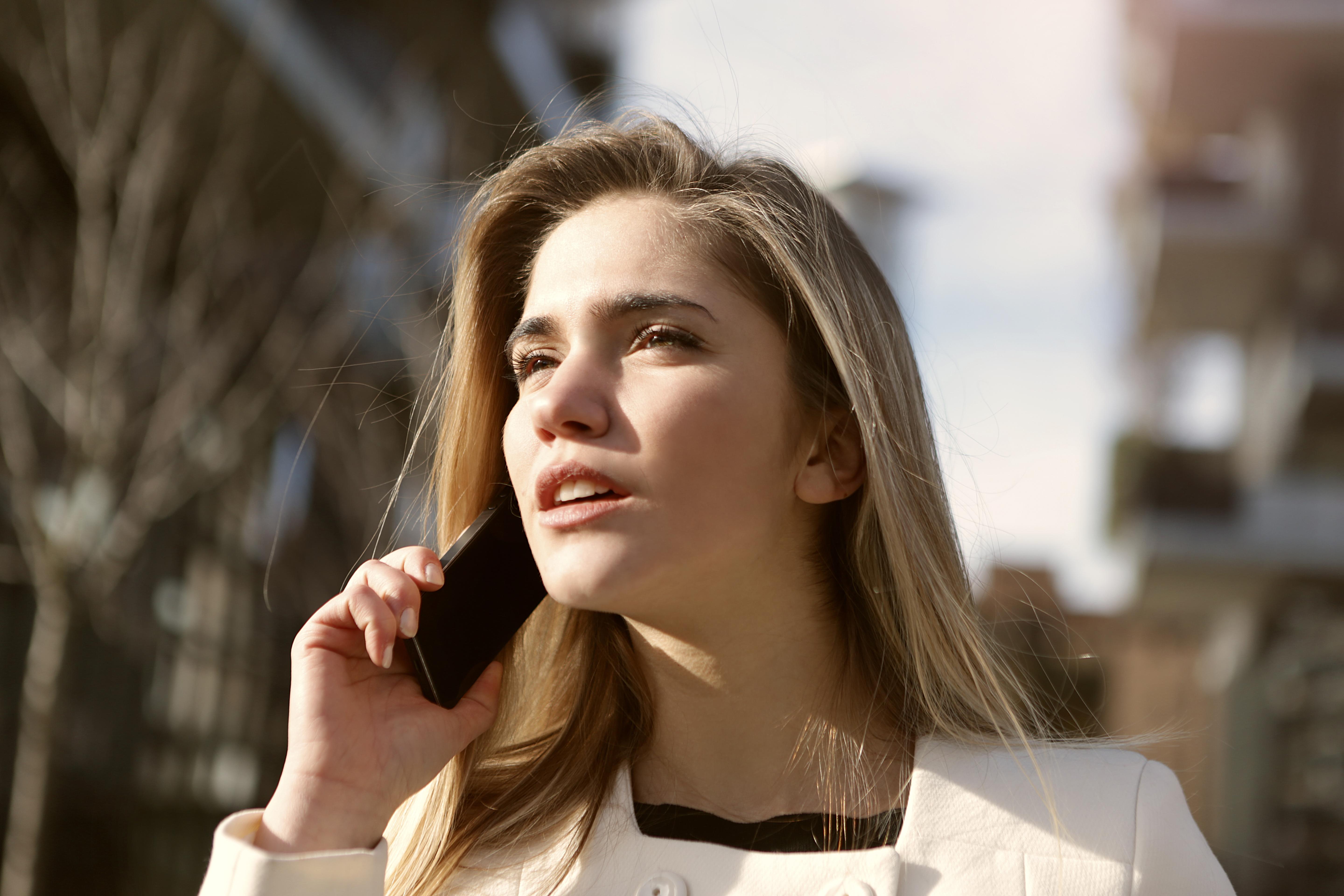 wp content/uploads///Canva Selective Focus Photography of Woman Standing Wearing White Coat Holding Smartphone