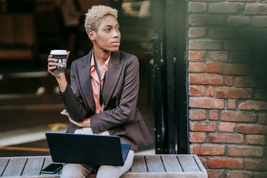 Woman holding coffee with laptop on lap 