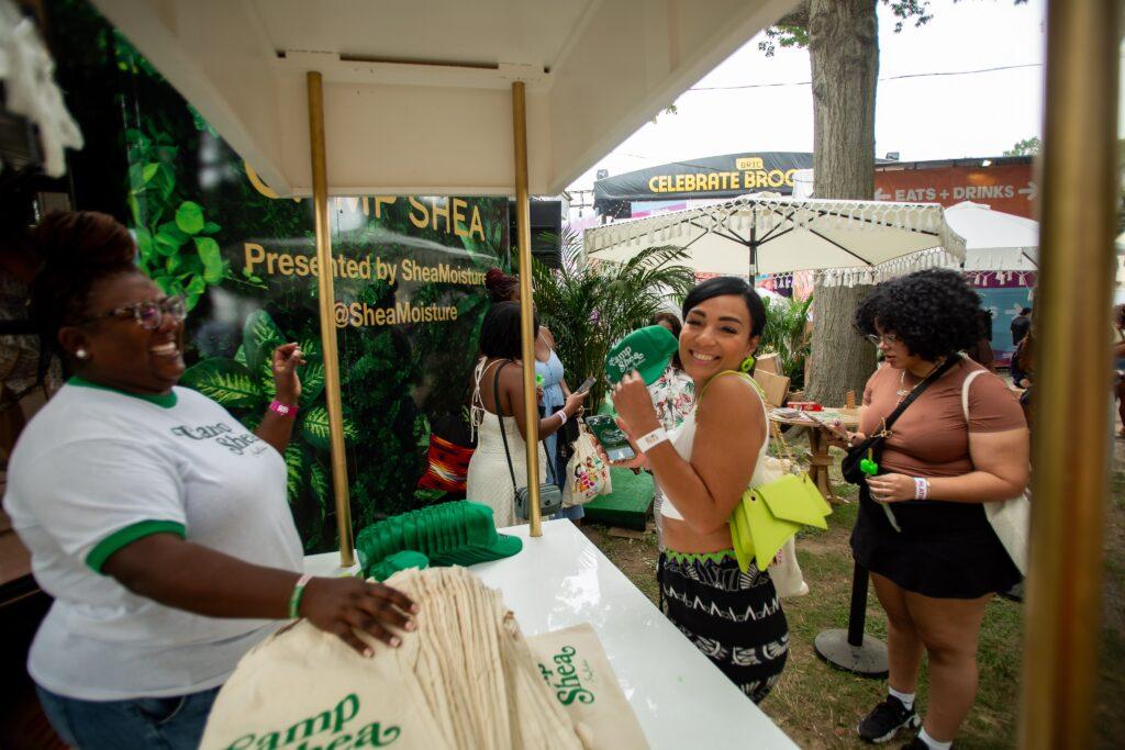 2024 CurlFest Attendees picking up green hats and tote bags from the Shea Moisture activation at the event