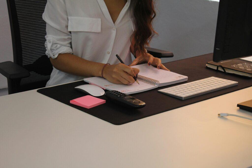 women writing in journal at desk