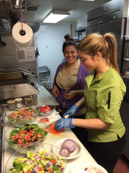 Gonca (left), and Arzu chop up some vegetables to add into a salad.