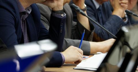 Participants in a business meeting with notebooks, pens, watches