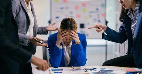 Businesswoman is feeling stressed while her coworkers are being aggressive and blaming her for something during a business meeting
