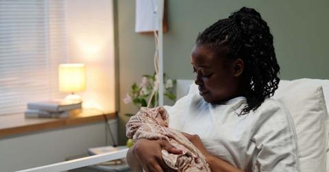 Cradling Newborn in Hospital Bed with Soft Lighting