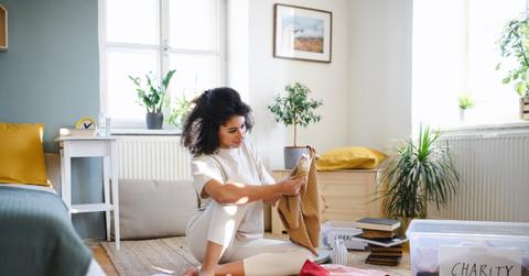 Young woman sorting wardrobe indoors at home, charity donation concept.