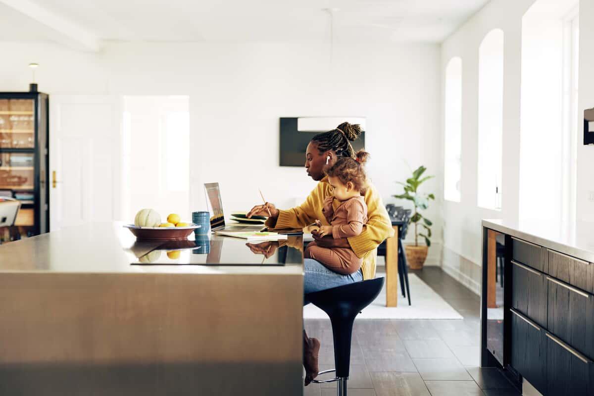 Young mom sitting with her daughter while working from home