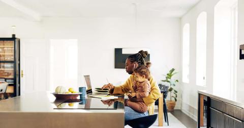 Young mom sitting with her daughter while working from home