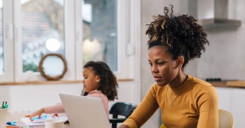 Mom is working from home with her daughter sitting next to her