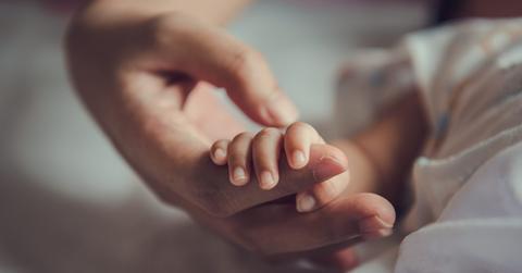 Newborn baby holding mother’s hand.