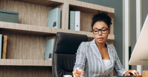 Serious businesswoman working on computer and taking notes in modern office
