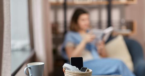 gadgets in basket on table and woman reading book