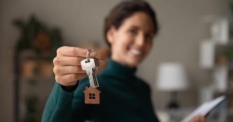Close up focus on keys, smiling woman realtor selling apartment