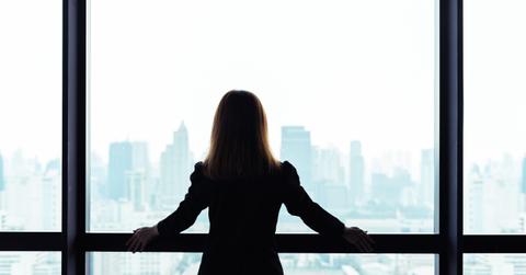 Asian business woman standing and looking out the window at city view background
