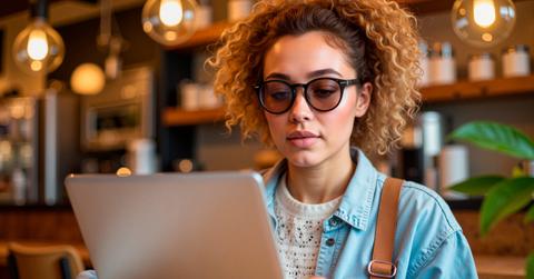 Focused woman working on laptop in cozy café, productivity and comfort