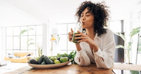 Young african american woman drinking green juice with reusable