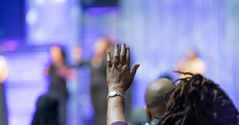 African American Woman in a Red Dress with Her Hand Raised in Church