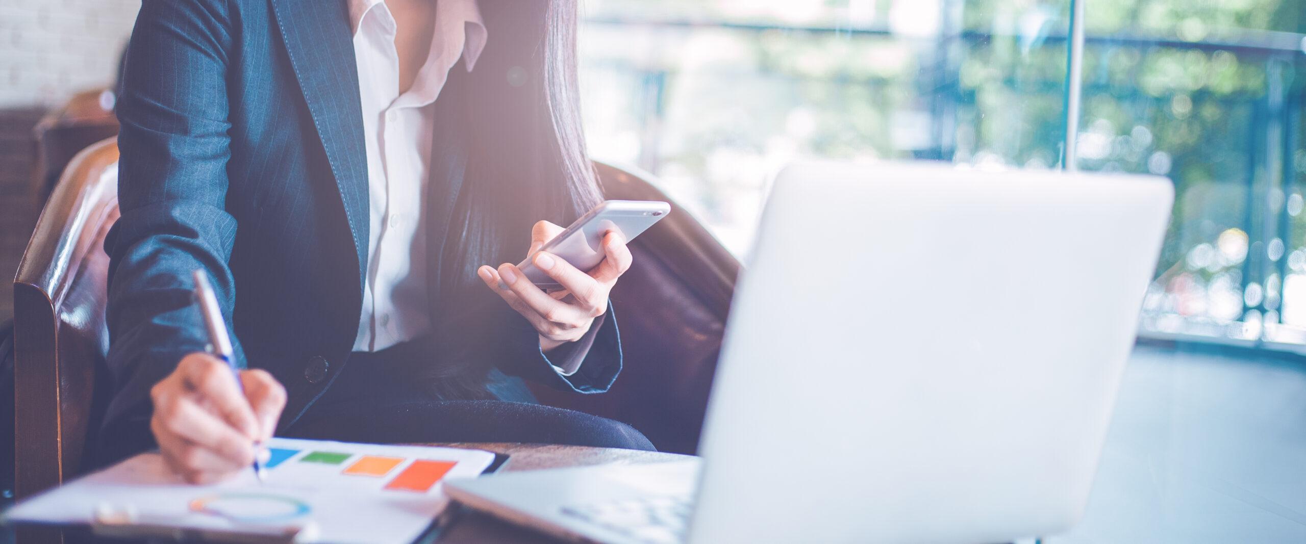 Business  woman uses a smartphone and writing on charts and grap