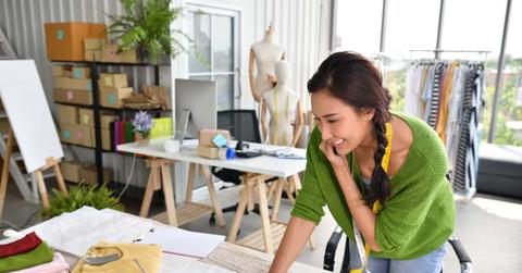 Young Asian woman entrepreneur / fashion designer working in studio