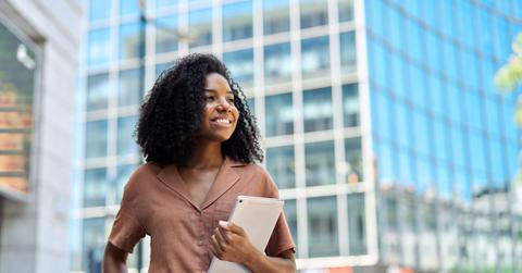 Happy young African American professional woman looking away standing in city.