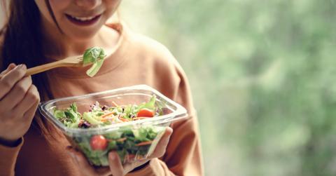 Closeup woman eating healthy food salad, focus on salad and fork