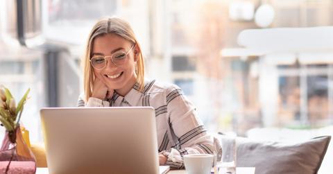 Portrait of young woman using laptop at cafe, she is working on