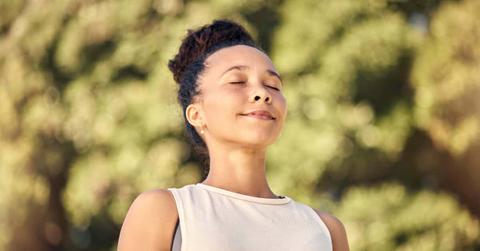 Black woman, happy and doing meditation exercise breathing, smile and outdoor for wellness, being calm in nature. Bokeh, African American female and healthy girl being peaceful, workout and yoga.