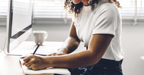 Portrait of african american black woman relaxing using technology of desktop computer while sitting on table.Young creative african girl working and write on book at home.work from home concept