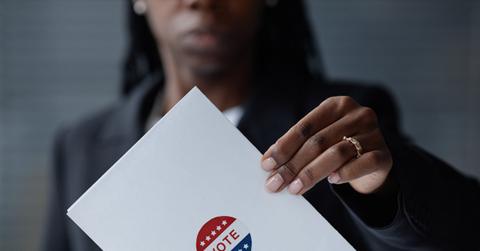Black Woman Submitting Ballot in Voting Box at Polling Station
