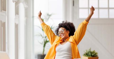 Joyful business woman freelancer entrepreneur smiling and rejoices in victory while sitting at desk and working at laptop after finishing project in home office