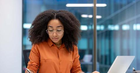 Serious accountant doing paperwork, woman working with documents, contracts and invoices. Office worker at work with laptop filling out financial reports