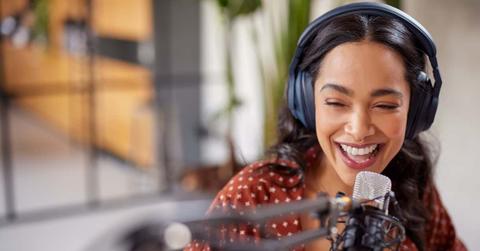 Joyful multiethnic woman recording live podcast