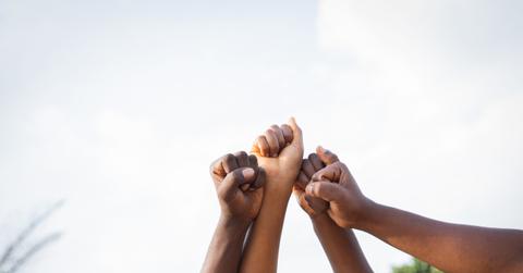Four fists of African people united in sky, photo with copy space.