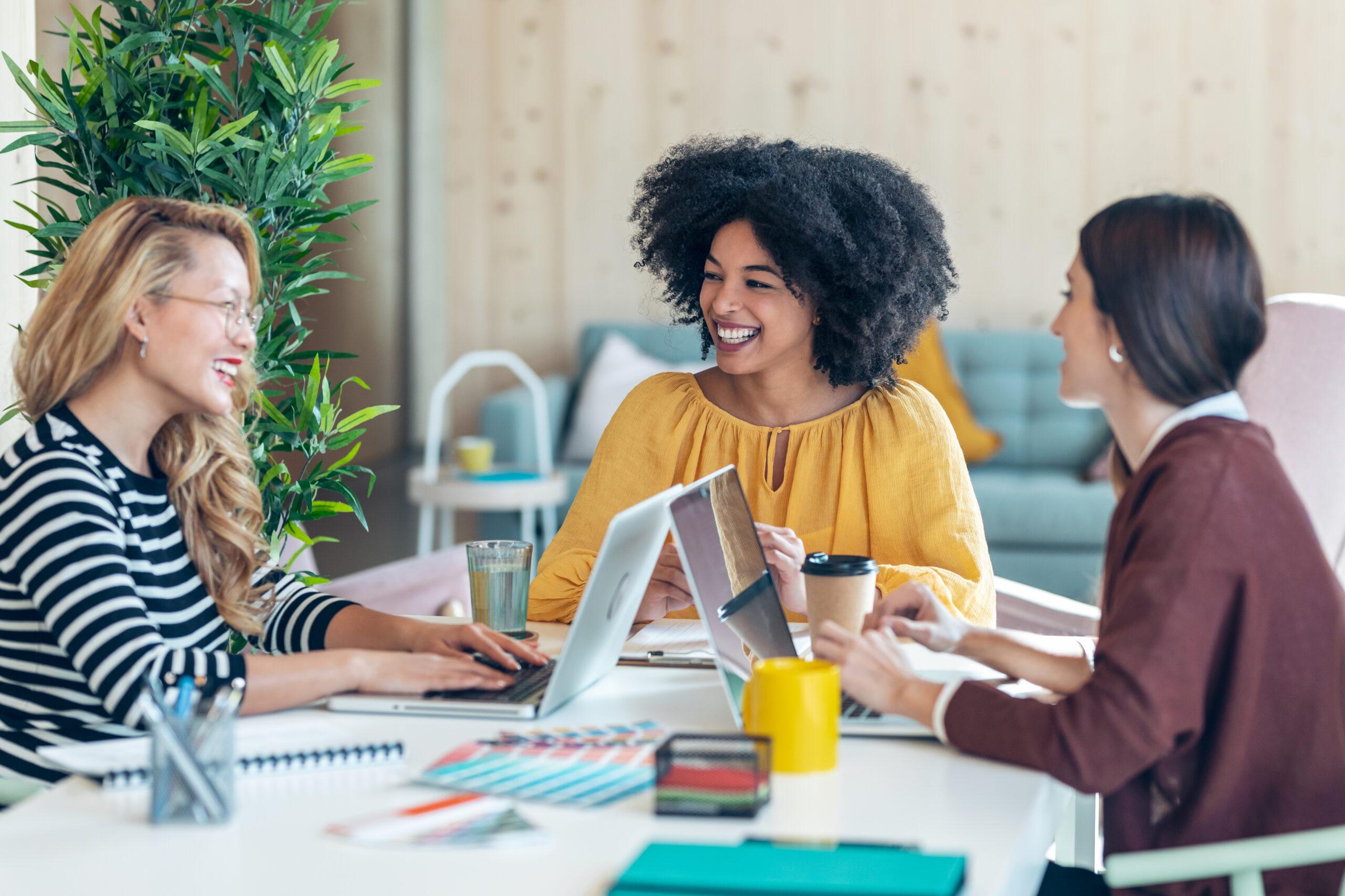 Casual multiethnic business women working with laptops while talking of they new projects together in coworking place.