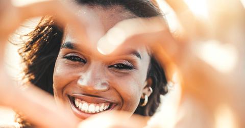 Beautiful young woman making heart shape with hands – Happy black woman smiling at camera outdoors – Health care and self love concept