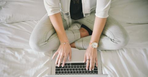 Wonans-Hands-With-Jewelry-Typing-On-Laptop-Sitting-On-A-Bed