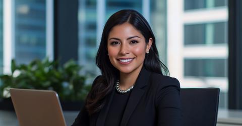 Professional woman working on laptop in modern office with city view