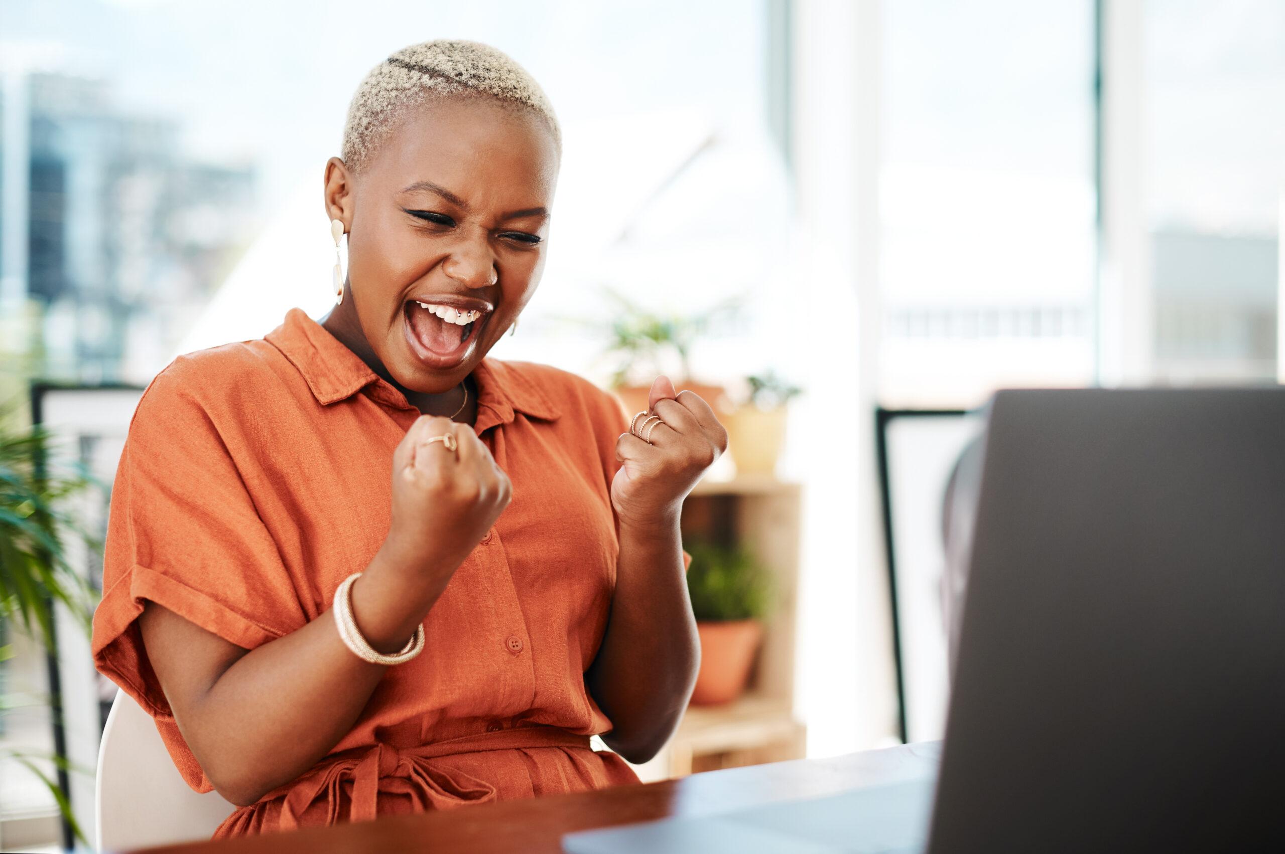 Business, fist and black woman with success, celebration and achievement in a workplace. Female employee, person and entrepreneur with happiness, startup and cheering with good news, email and goals