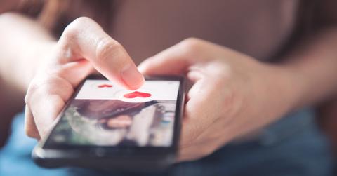 Finger of woman pushing heart icon on screen in mobile smartphon